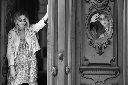 Fashionable woman face near vintage gate on the street, fashion street style.の写真素材