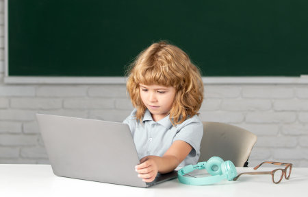 Child boy using a laptop computer at school.