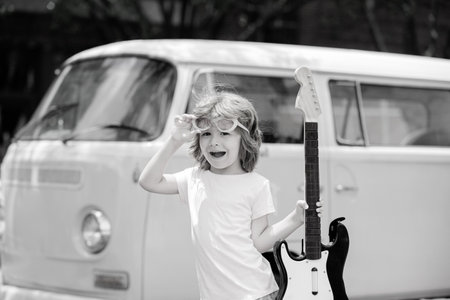 Funny little hipster musician child playing guitar.の写真素材