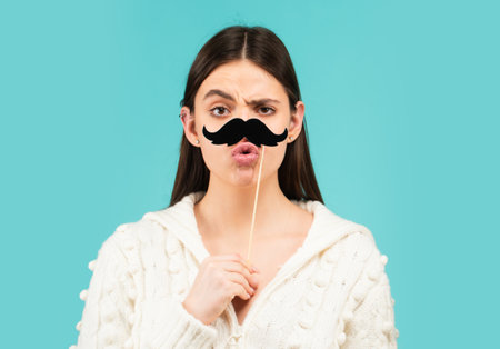 Girl, moustache and happy with prop. Comic woman portrait. Funny face with moustache on stick. Funny woman holding paper moustache party stick. Girl holding funny mustache.の写真素材