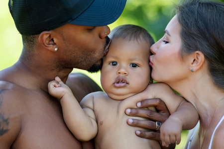 Multiethnic parents and amazed mixed race baby. Multiethnic family outdoor portrait. Happy Multiethnic family hug baby child. Beautiful diverse family. Multiethnic family have fun together.の写真素材