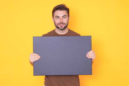 Man with blank banner ad on studio background. Portrait of attractive man holding empty blank...