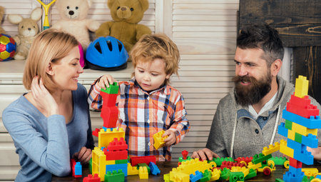 Family playing with colorful plastic building blocks at home. Happy family fun. Mother and father play with their son. Early childhood development, kids creativity. Family bonding. Family of 3.の写真素材
