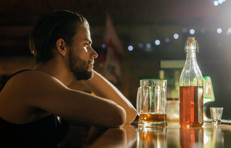Drunk man sitting alone in bar. Alcoholic man drink whiskey. Sad man at restaurant. Young guy...