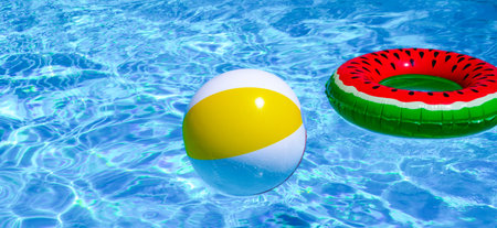 Summer day by the pool. Floating beach ball on pool water. Summer background. Inflatable toy. Summer...