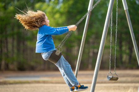 Happy child enjoying a fun ride. Happy kid on playground. Carefree kid swinging in the air. Happy...