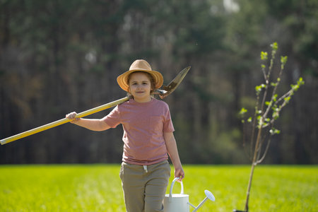 Child planting tree with shovel. Kid planting tree on backyard. Child planting tree in spring field.の写真素材