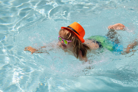 Child in swimming pool. Summer lifestyle. Swim water sport activity on summer vacation with kids....