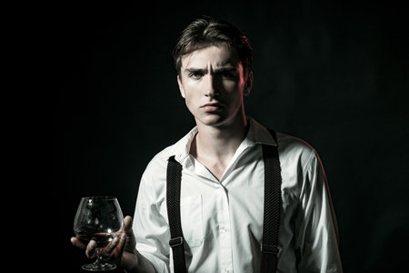 Man drinking whiskey at bar. Handsome man enjoying a drink. Whiskey moment with serious face. Man holding classic whiskey glass. Man tasting aged whiskey alone.の写真素材