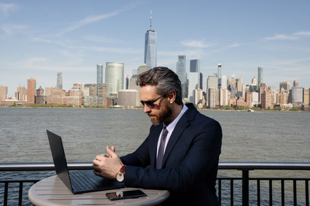 Successful USA businessman. Man using laptop outdoor in New York City. Business success. American business dream. American businessmen in suits with laptop near Manhattan. Online business in US.の写真素材
