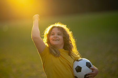 Happy child playing soccer. Kid boy kicking a football on the grass. Kid running with a soccer ball. Playful children enjoying a football game. Kids soccer match. Kid playing football kicking a ball.の写真素材