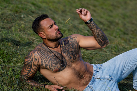 Sexy farmer man on summer field. Muscular sexy farmer rest on summer nature. Farmer posing in rural summer countryside. Shirtless sexy model relaxing on a ranch. Topless muscular guy rest on summer.の写真素材