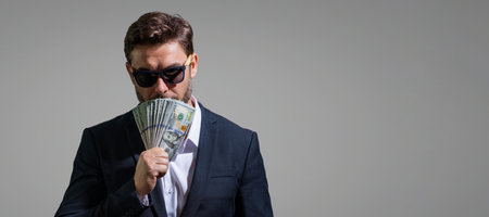 Business man hold money on gray studio isolated background. Rich man in suit with money dollar bills. Businessman with dollar banknotes. Rich millionaire in suit holding money. Banner copy space.の写真素材