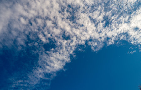 Blue sky with calm clouds background. Bright blue sky background. Cloudscape with white clouds. Calm sky cloudy on a summer day. Sunlight through the clouds wallpaper. Spring sky with soft clouds.の写真素材