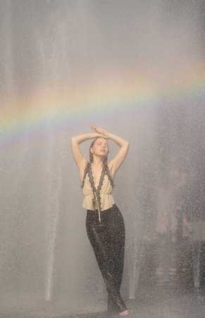 Hot summer Young woman splashing in a city fountain. Wet girl in fountain on hot summer day. Playful funny moment during a summer vacation. Fountain fun on summer. Funny woman traveler or tourist.の写真素材