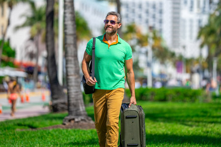 Mature man 40s traveler. Tourist on spring vacation. The travelers luggage for spring trip. Summer tour. A tropical getaway. Spring break. A traveler enjoys summer day. Spring trip.の写真素材