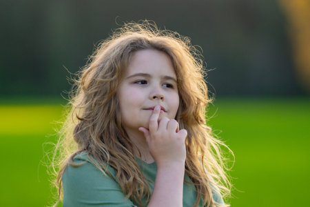Kid looking away. Child thinking with a doubtful look. Portrait of a child imagining deeply. Dreamy teen child lost in thought. Clever boy with thoughtful face. Daydreaming child showing quiet wisdom.の写真素材