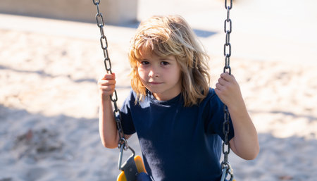 Swinging on playground. Little child having fun on a swing outdoor. Summer playground. Kid swinging high.の写真素材
