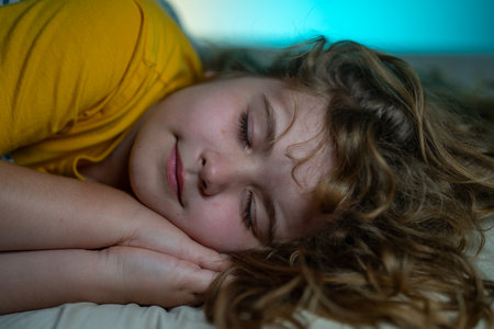 Child sleeping in a bed. Cute kid sleep. Kids pillow and blanket for sleeping. Kid sleeping in dark bedroom. Child sleeping on a bed at home.の写真素材