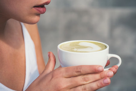 Sensual woman drinking espresso. Attractive brunette holding coffee cup. Girl enjoying aromatic latte. Romantic portrait of woman with coffee in cafeteria. Model with coffee glass. Delicious coffee.の写真素材