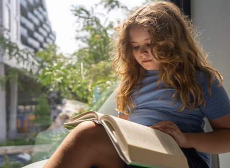 Cute blonde child reading book at library. Kid studying and reading. Smart kid read book. Little student learning from book. Child reading book in library. Knowledge through reading.の写真素材