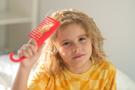 Funny child hairstyle. Child with curly hair hold hairbrush or comb. Healthy hair. Kid brushing unruly tangled hair.の写真素材
