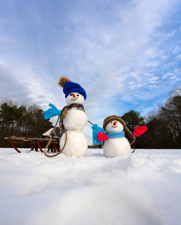 Snowman in winter background. Snowman in winter holiday. Decorated snowman. Greeting card for New Year and Christmas poster. Family snowmen with snow winter background. Xmas winter banner.の写真素材