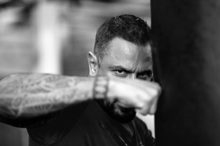 Serious danger man boxing punching bag. Man boxer face close up. Knockout. Fists fight. Sport Man ready for boxing challenge. Mans fight. Boxing fight. Boxing sport.の写真素材
