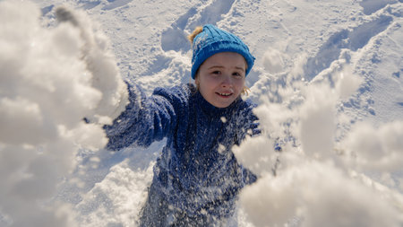 Winter child. Funny child playing in the snow. Kid play in snowy winter park. Winter fun with...