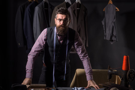 Tailor, tailoring. Man suit, tailor in his workshop. Costume suit tailoring. Man tailoring jacket. Tailor on workshop. Tailored suit. Mens suit. Bearded man is a classic tailor.の写真素材