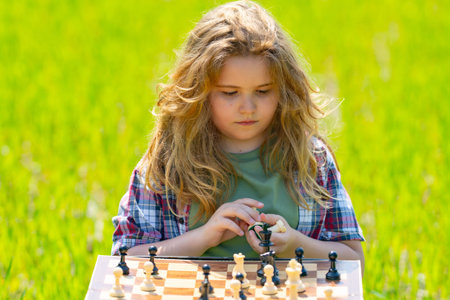 Kid plays chess. A child thinks and playing chess. Kid focuses on chessboard. The kid make...