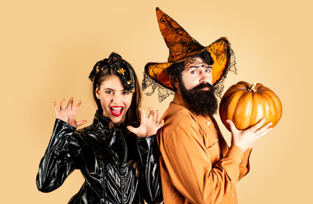 Happy couple in Halloween costume. Halloween couple with pumpkin and Halloween makeup. Man and woman in witch hat celebrating Halloween.の写真素材