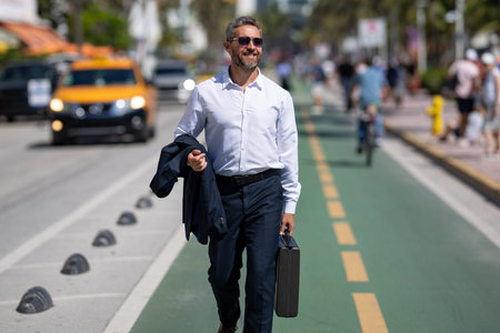 Mature businessman walking confidently in the city. Business man walking down the street. Handsome businessman walking on way to the office. Confident entrepreneur walking outdoors.の写真素材