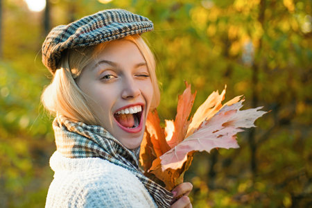 Autumn woman with fall yellow maple leaf near face, outdoor portrait. Girl with autumn leaves....