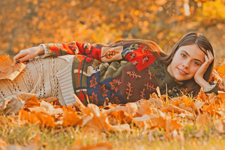Autumn woman posing in golden sunlight. Stylish girl with fall leaves. Romantic portrait with autumn...