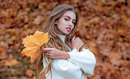 Woman with autumn leaves of maple trees. Woman near autumn fall leaves in sunlight. Natural beauty girl on autumnal fall background. Foliage, falling leaves background, autumn leaf and people concept.の写真素材