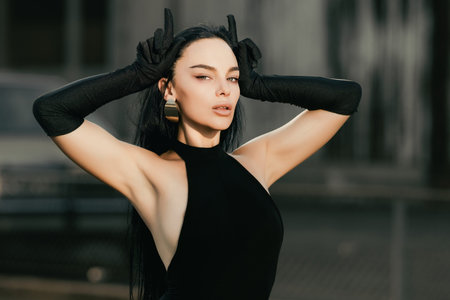 Fashion Brunette model girl shows fingers horns. Glamour woman doing gesture with finger over head...
