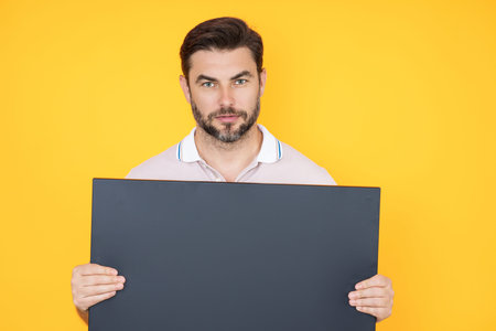 Man with empty blank banner ad on studio background. Portrait of attractive man holding empty blank...