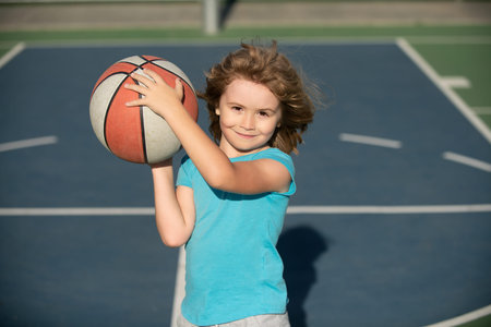 Child playing basketball on outdoor court. Happy child boy hold basketball ball. Summer sport kids. Child on basketball game. Sporty child training basketball. Outdoor sport for children.の写真素材