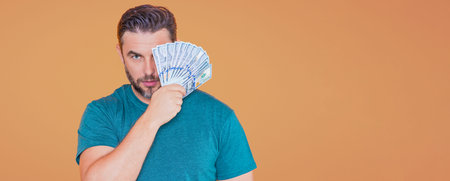 Business man in t-shirt with cash money dollars banknotes isolated on yellow studio background....