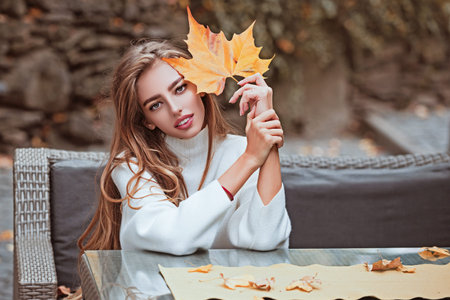 Autumn woman in golden sunlight. Romantic portrait of stylish girl with leaves. Beautiful woman face...