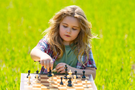 Kid plays chess. A child thinks and playing chess. Kid focuses on chessboard. The kid make checkmate. A smart kid plans chess.の写真素材