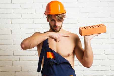 Crazy builder with bricks, funny sale on construction site. Funny man hold brick. Builder posing with bricks blocks. Bricklayer concept. Funky handyman. Man in hardhat holding brick. Crazy builder.の写真素材