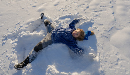 Child play in snowy park. Kid plays in falling snowflakes. Winter fun. Portrait of kid in winter....