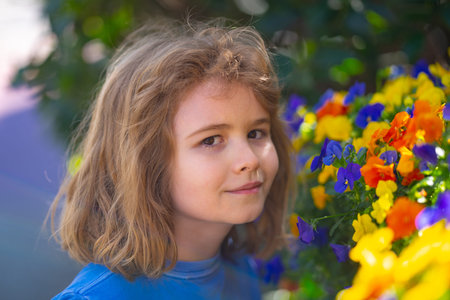 Cute blonde kid boy in spring garden. Little child under a blossom tree. Happy kid playing under blooming cherry tree. Kid with flower on Easter. Adorable kid in blooming cherry garden on spring day.の写真素材