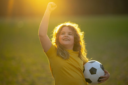Child playing soccer. Kid boy kicking a football on the grass. Kid running with a soccer ball. Playful children enjoying a football game. Kids soccer match. Kid playing soccer kicking a ball.の写真素材