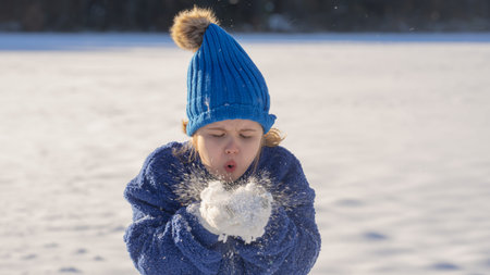 Kid in snowy winter park. Winter child plays with snowflakes. Kids winter holidays. Childhood...
