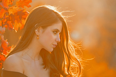 Autumn woman portrait in autumn fall. Woman with fall leaves. Romantic portrait in autumn foliage. Model on autumn nature. Woman with falling leaves.の写真素材