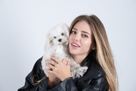 Woman hugging fluffy puppy outdoors. Girl playing with cute dog. Young woman holding small white...