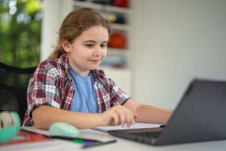 Child study at home with laptop and books. Kid learning in a cozy home classroom. Kid study at...